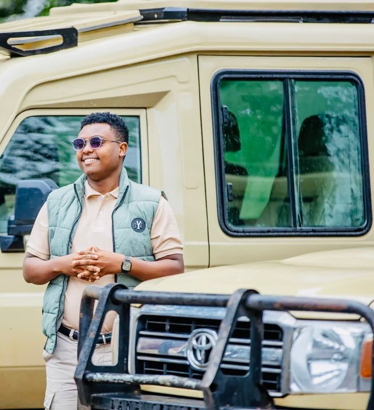 Naaman Kissila of Tanzania Simplified Safaris beside a safari vehicle